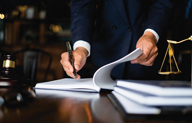 Professional signing documents beside scales of justice