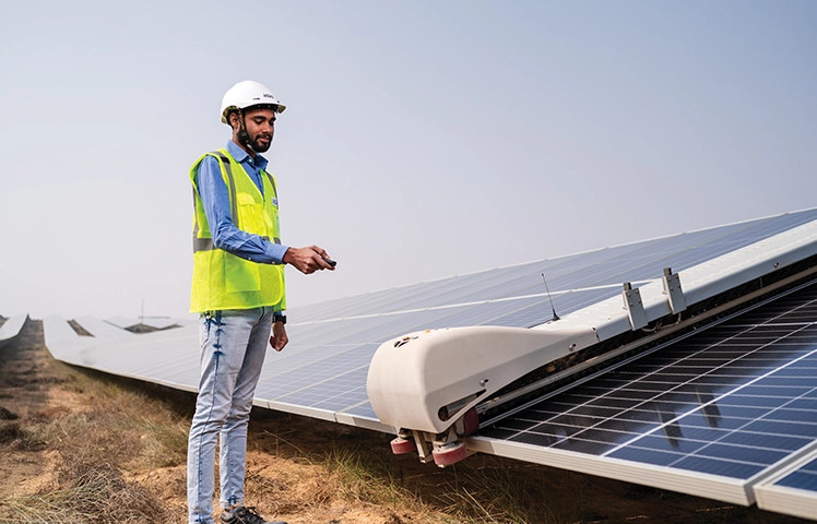 Engineer with robotic solar-panel cleaning module at a solar farm