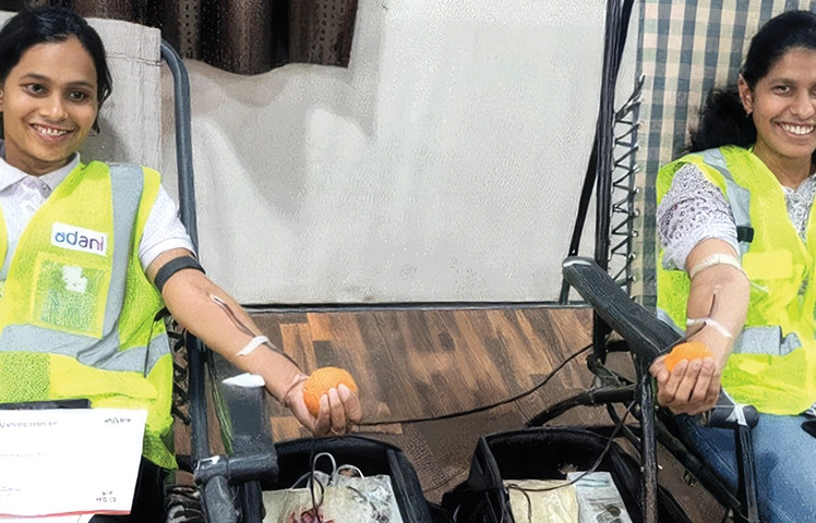Women employees in AGEL vests donating blood