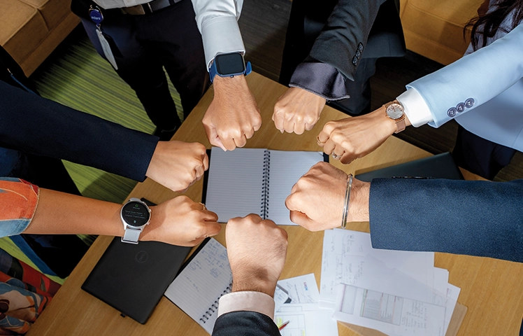 Team members' hands joined over a table (unity)