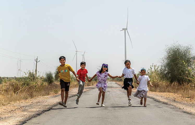 Bhimsar, Rajasthan - children running, wind farm behind